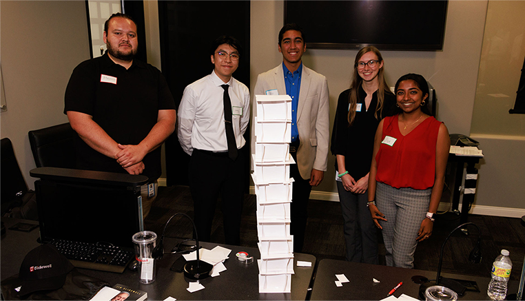 Interns posing for a photo behind a stack of paper boxes